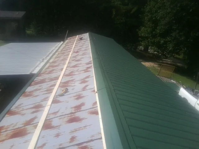 Old rusted panels beside newly installed green metal roofing — Wind Damage Roof Repair by Roofing Brothers in Basalt