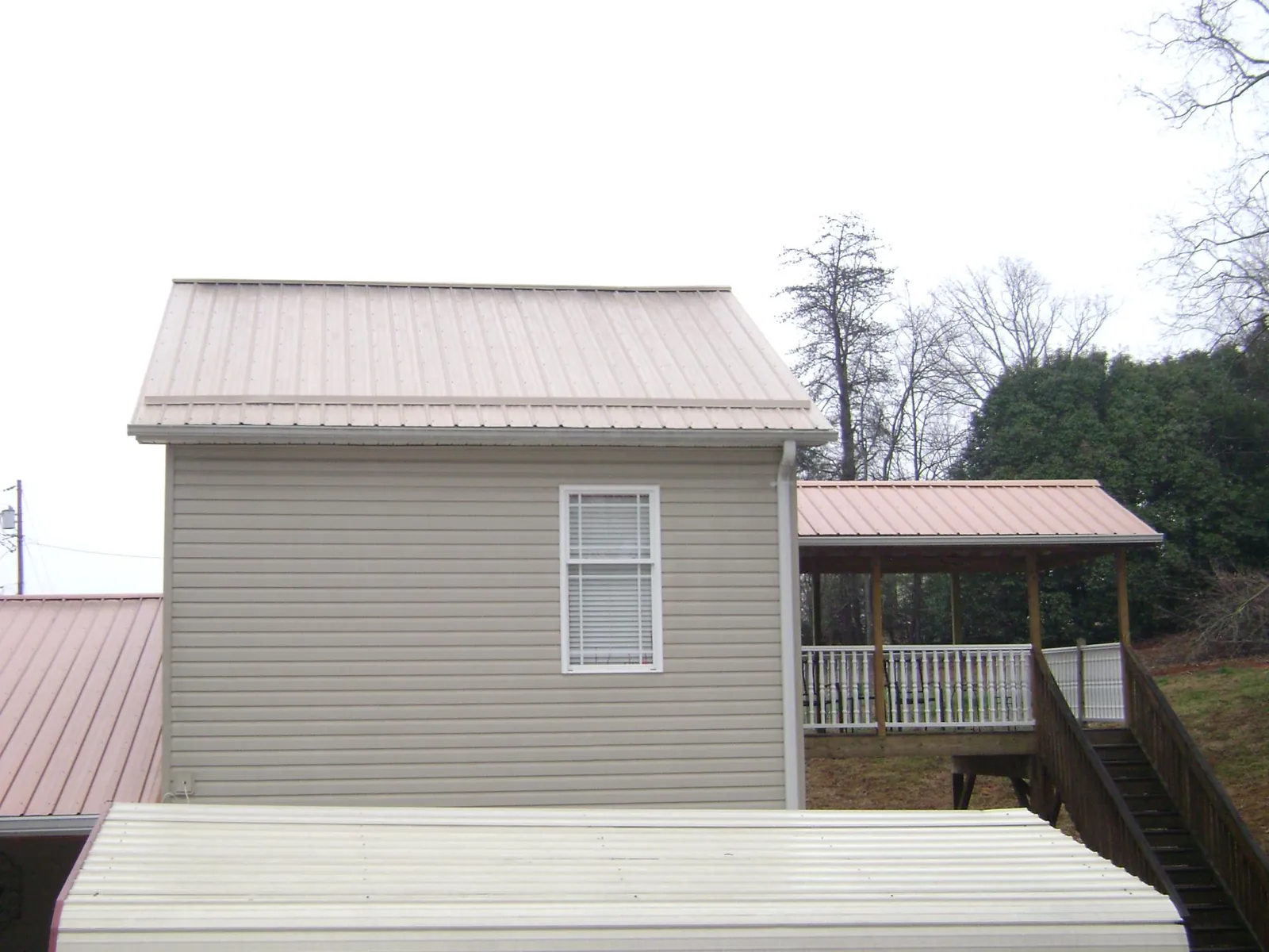 Tan metal roofs on a two story addition and attached porch, from a Roof Replacement job in Basalt